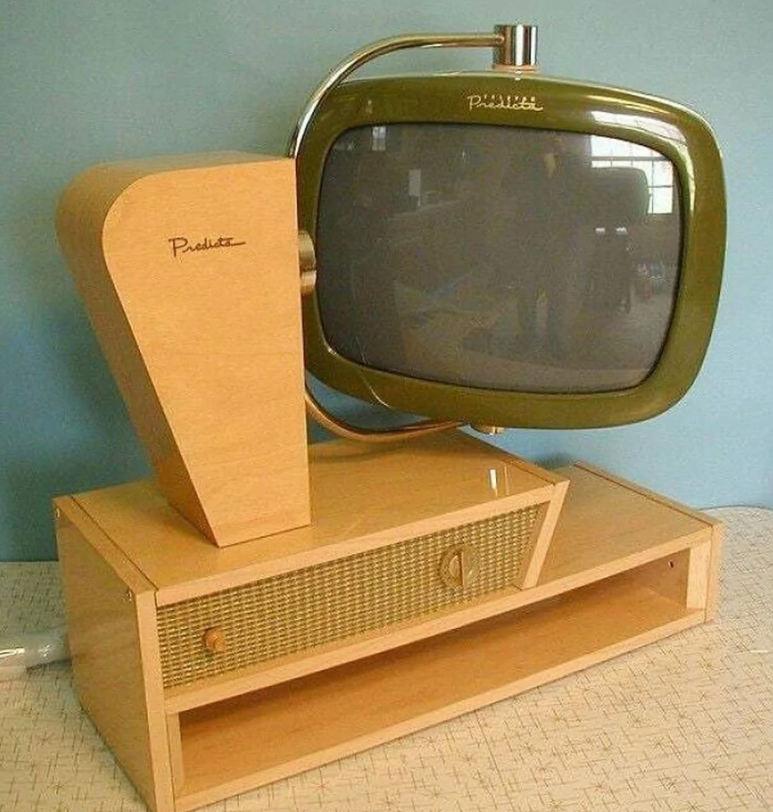 Retro televízor s dreveným podstavcom a zeleným orámovaním obrazovky proti modrej stene.