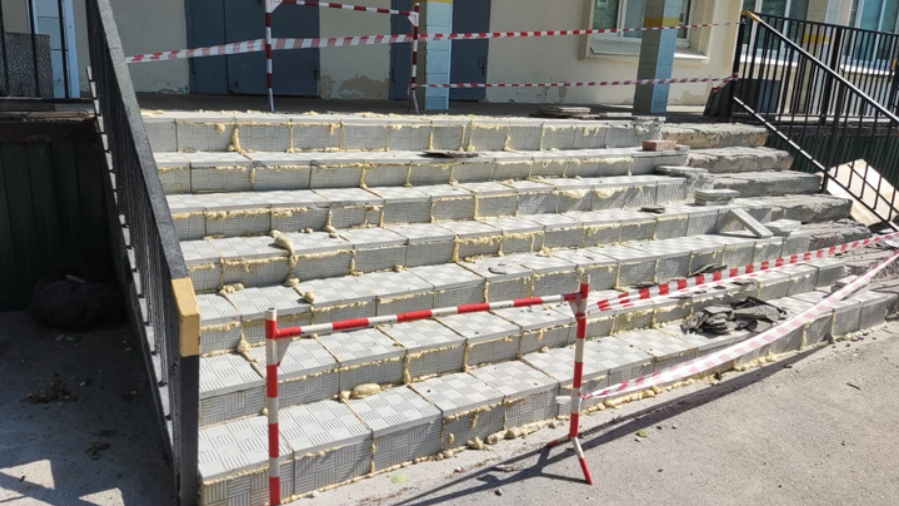 Zrekonštruované schody s tehlovým obkladom a bezpečnostnou páskou, pripravené na dokončenie.
