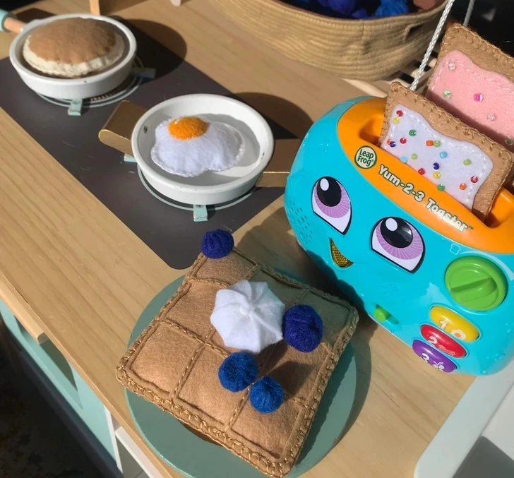 Detská kuchynka so zábavným hriankovačom a plstenými potravinami, vrátane vajíčka a toastu.