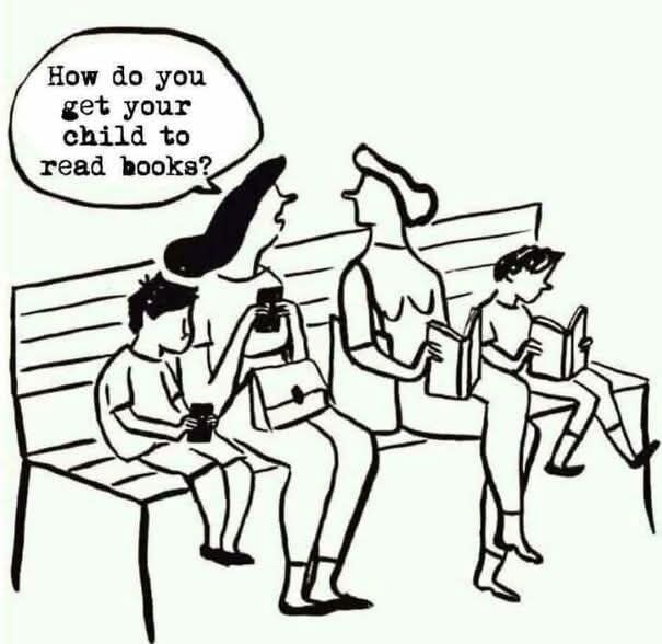 Mamičky na lavičke diskutujú o tom, ako zaujať deti čítaním kníh; jedno dieťa už číta vedľa nich.