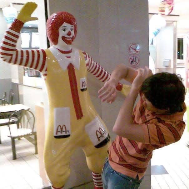 Osoba sa hrá so sochou klauna vo fastfoodovej reštaurácii.