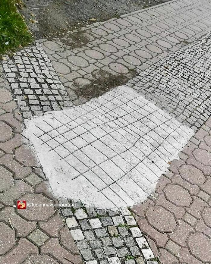 Nerovnomerná úprava chodníka s odlišnými dlaždicami a betónom, vtipný pokus o opravu povrchu.