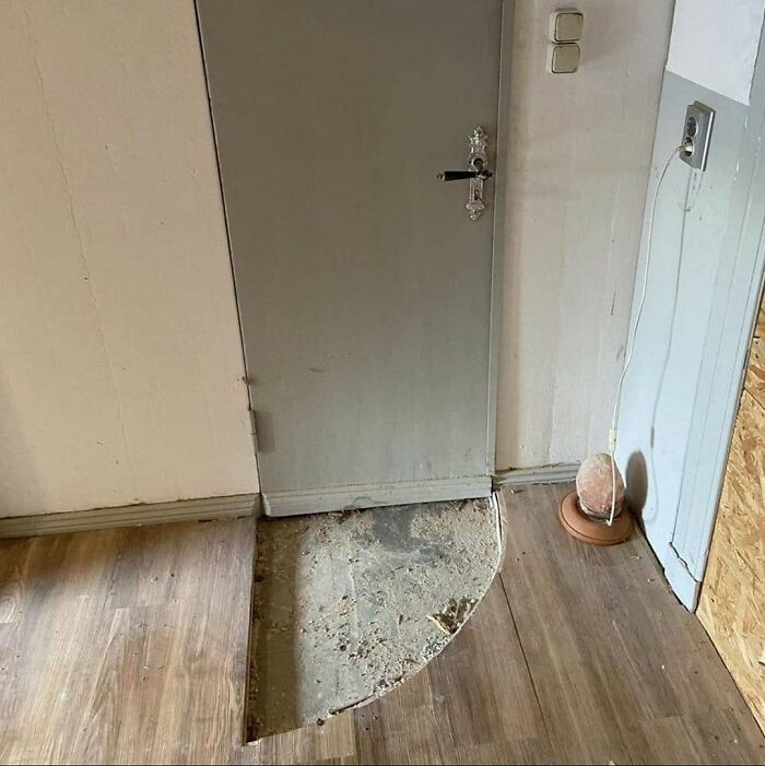 Dvere nad podlahou s výrezom pre otváranie, vedľa soľná lampa na drevenej podlahe.