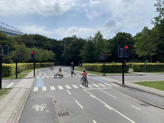 Deti na bicykloch prechádzajúce cez farebnú cyklocestu so semaformi v parku.