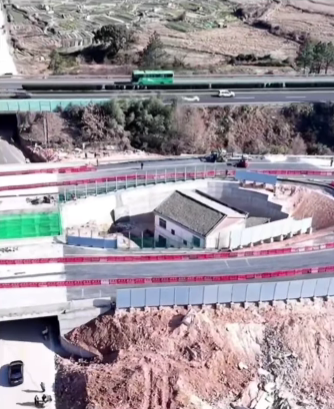 Dom obklopený cestnou infraštruktúrou s výrazným mostom nad ním; obrázok zobrazuje konštrukciu v spojení s prírodou.