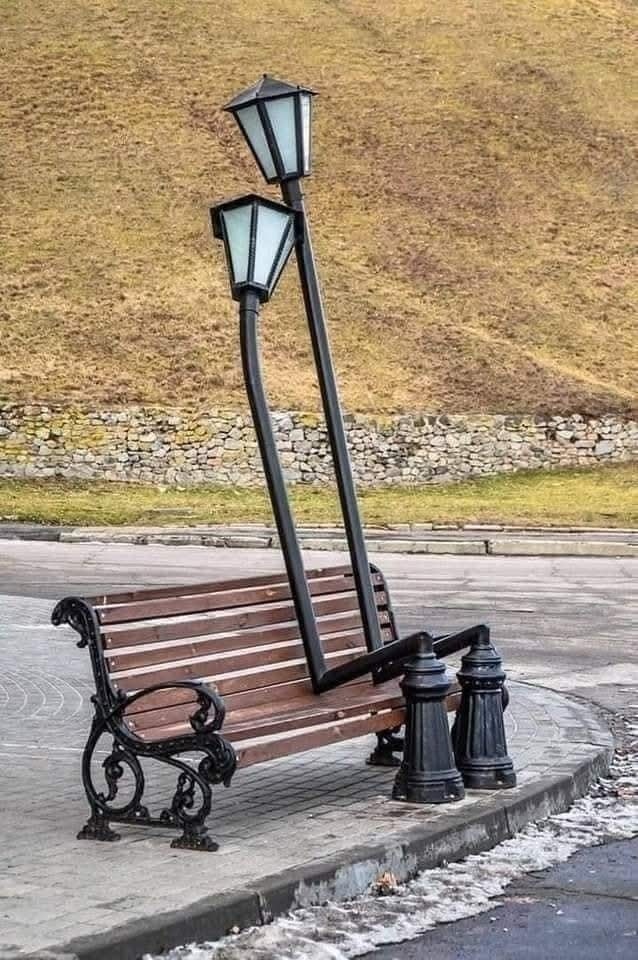 Dve pokrivené pouličné lampy na lavičke v parku, vytvárajúce humoristický vizuál.