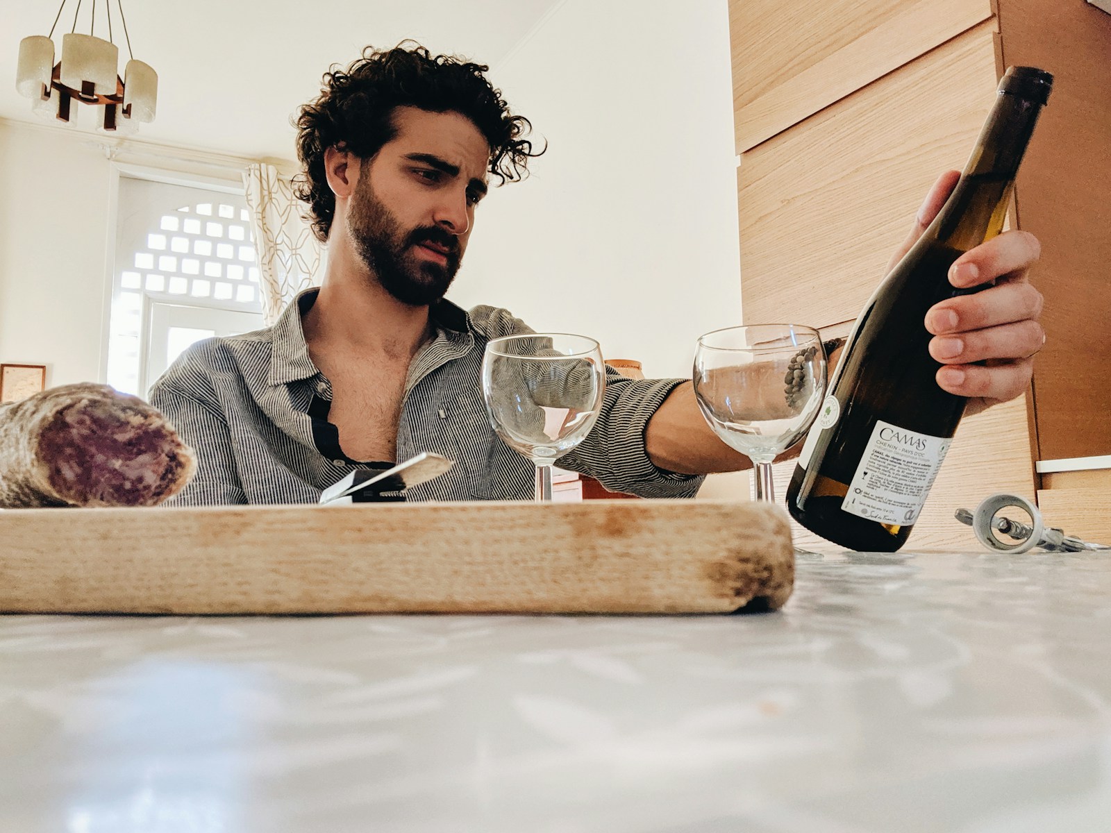 man holding white glass bottle sitting beside table