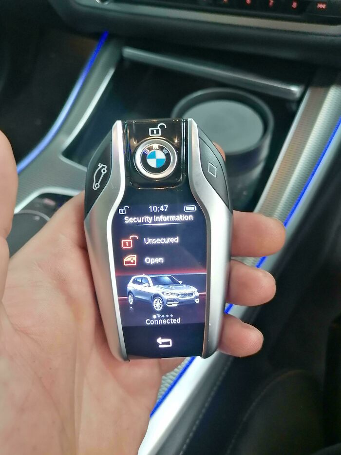 Inteligentný kľúč od automobilu v ruke so zobrazeným displejom a logom automobilovej značky.