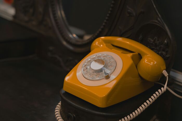 Žltý retro otočný telefón na starožitnom stole, nostalgický dizajn jedinečnej klasiky.