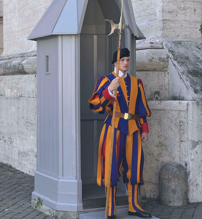 Švajčiarsky gardista v tradičnej farebnej uniforme stráži vatikánsky vchod.