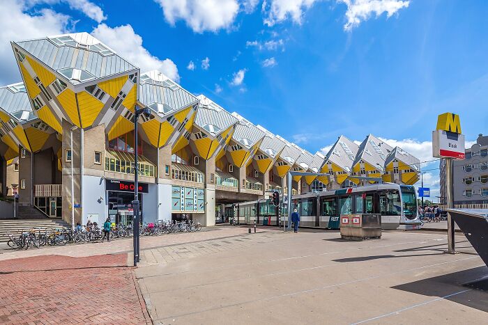 Žlté naklonené kockové domy v Rotterdame pri električke.
