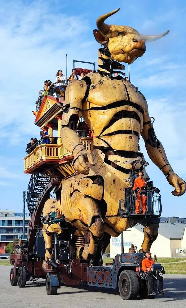 Obrovský drevený mechanický minotaurus počas pouličného festivalu s ľuďmi jazdiacimi na jeho chrbte.
