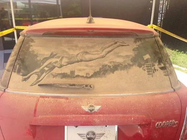 Auto so zadným sklom pokrytým prachom, na ktorom je nakreslený obrázok potápača.