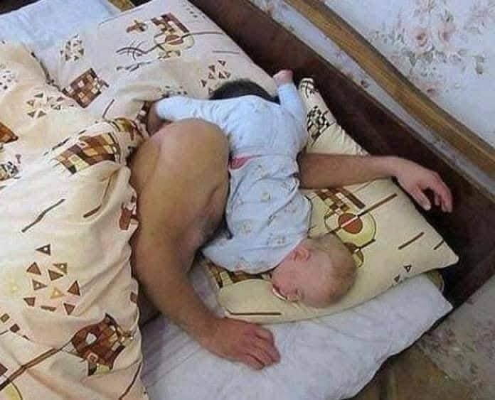 Dieťa pri tvári dospelého ležiaceho na posteli.