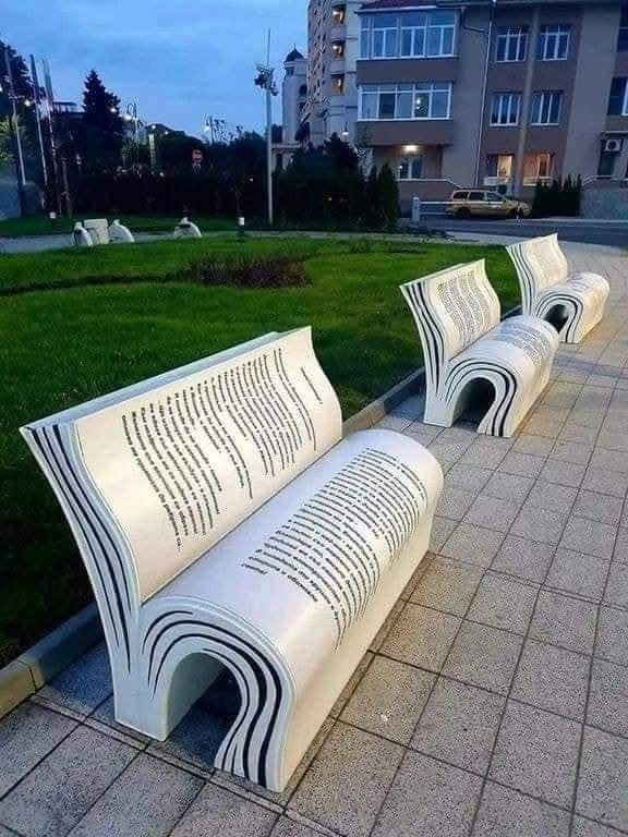 Lavičky v tvare otvorených kníh na námestí, ideálne pre knižných nadšencov a milovníkov originality.