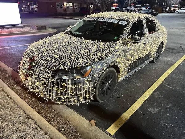 Auto pokryté svetielkami na parkovisku v nočnom meste, žiariace vo vianočnom duchu.