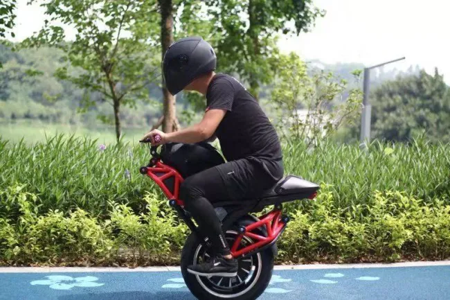 Jazdec na jednokolesovej elektrickej motorke v parku, obklopený prírodou.