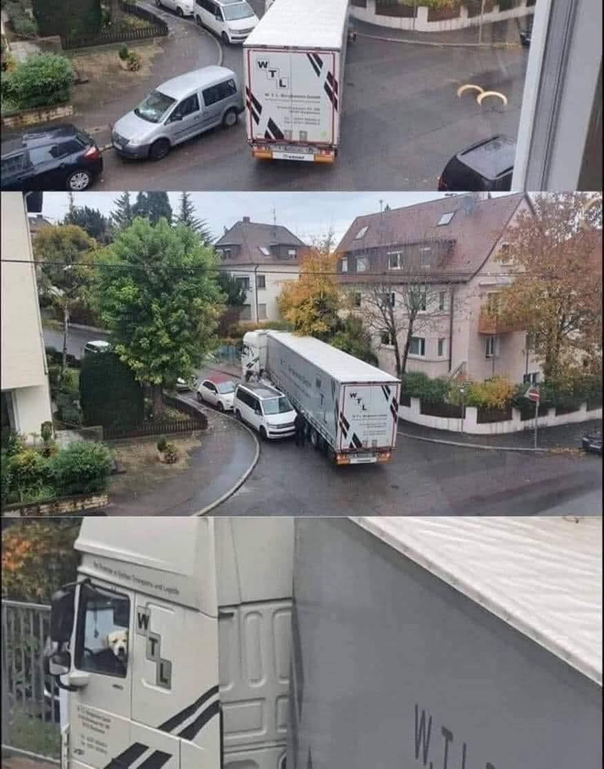 Nákladné auto v úzkej ulici blokuje viacero áut; pes v kabíne sedí na sedadle vodiča.