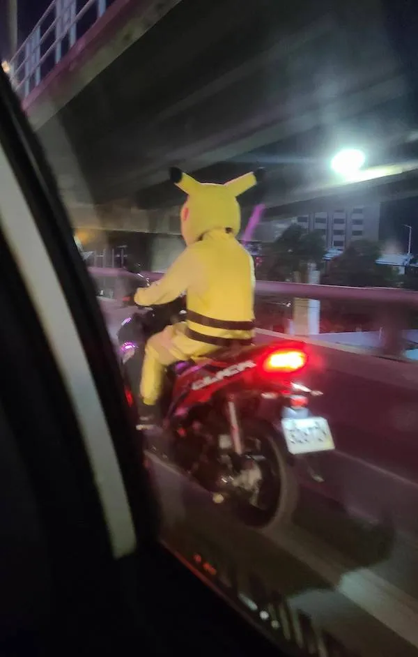Motorkár v žltej kostýmovej postave jazdí po ceste v noci pod mostom.