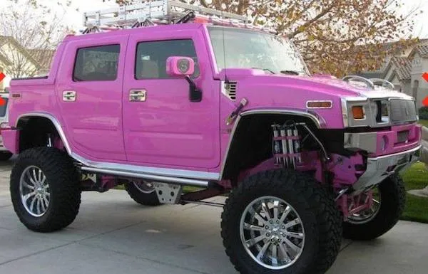 Ružový Hummer SUV s veľkými kolesami na príjazdovej ceste, zdvihnuté odpruženie, ideálne pre terénnu jazdu.