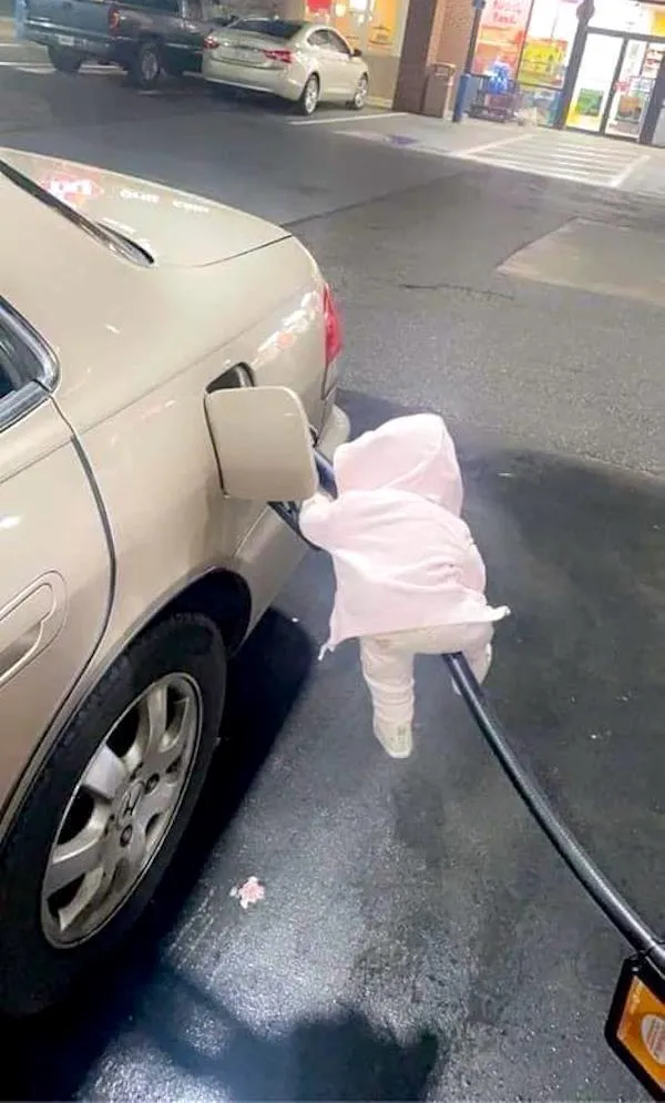 Plyšová hračka obliekač visí na kábli pri nádrži auta na čerpacej stanici za súmraku.