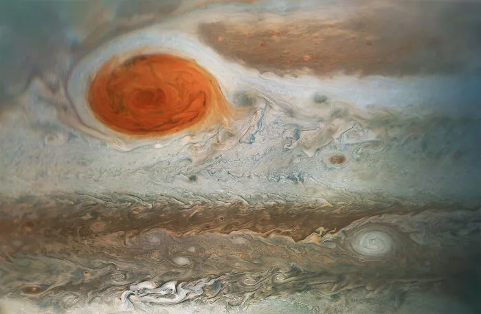 Veľká červená škvrna na Jupiteri obklopená vírmi a farebnými oblakmi atmosféry.