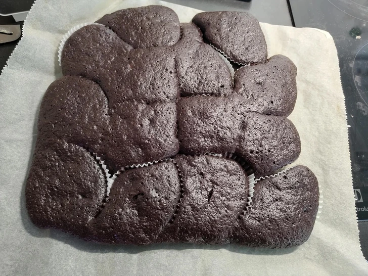 Domáce kakaové muffiny na plechu, pečené na papieri, pripravené na vychutnanie.
