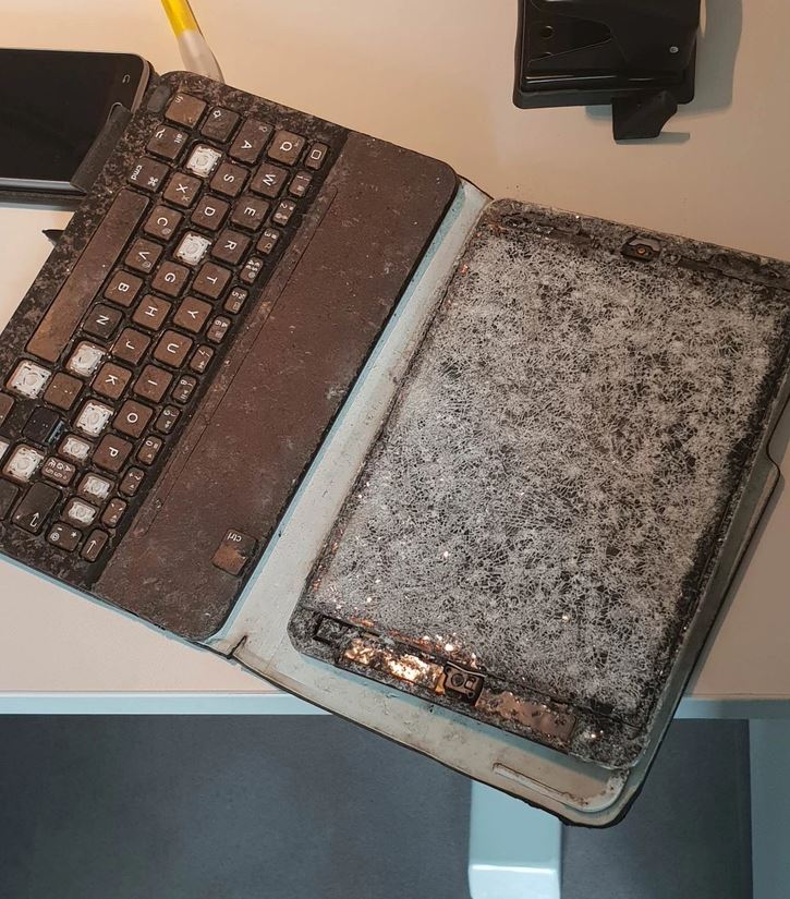 Starý, zaprášený laptop a tablet na stole, obalené vrstvou prachu a pavučín.