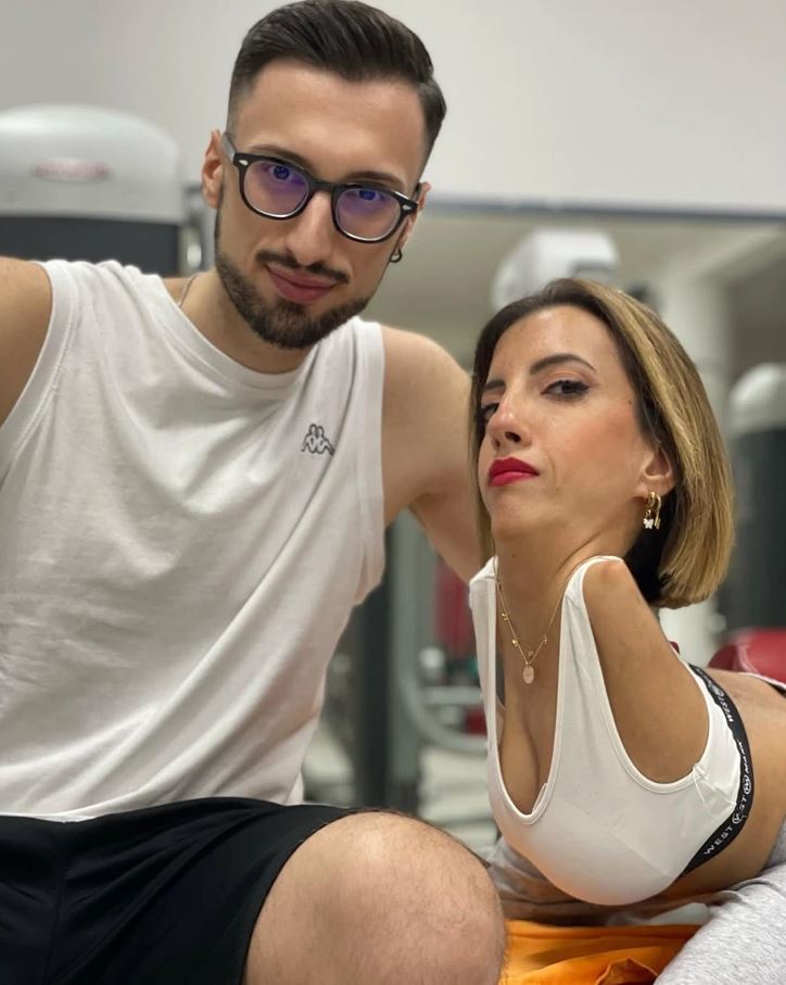 Prepáč, neviem identifikovať osoby na obrázku. Môžem ti však pomôcť s návrhom všeobecného alternatívneho textu.Ľudia v posilňovni počas tréningu, zameranie na spoluprácu a motiváciu.