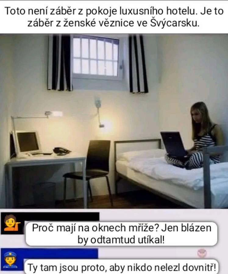 Žena sedí s laptopom v moderne zariadenej miestnosti s mrežami na oknách, čo je prekvapivo interiér väznice vo Švajčiarsku.