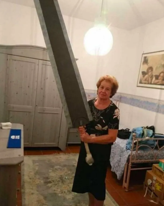Žena drží obrovský meč v izbe s retro nábytkom, svetlo visí nad ňou.