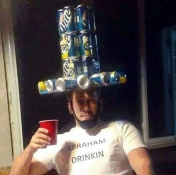 Muž s klobúkom z pivných plechoviek a tričkom Abraham Drinkin drží červený pohár. Zábavná momentka z párty.
