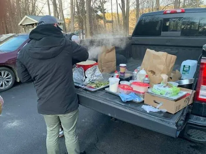 Osoba varí na zadnej časti pick-upu s rôznymi ingredienciami v prírode.
