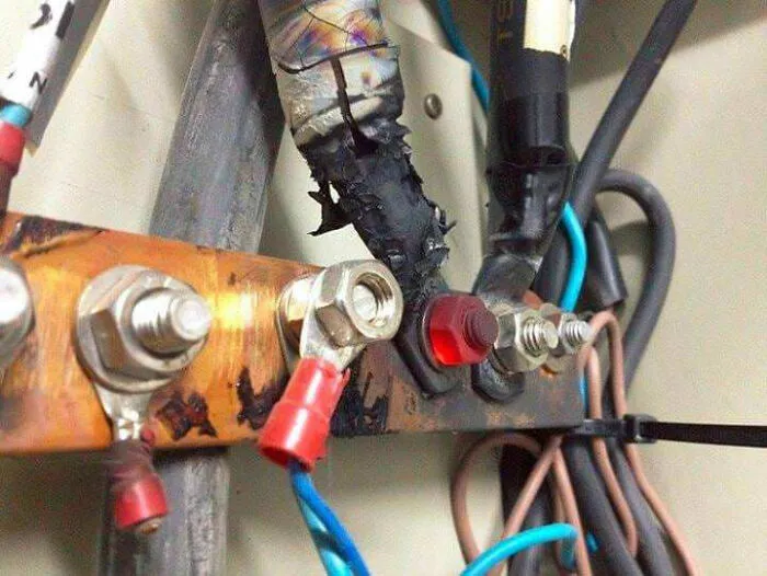 Elektrické pripojenie s poškodenou izoláciou, obnažené káble a matice, bezpečnostné riziko.
