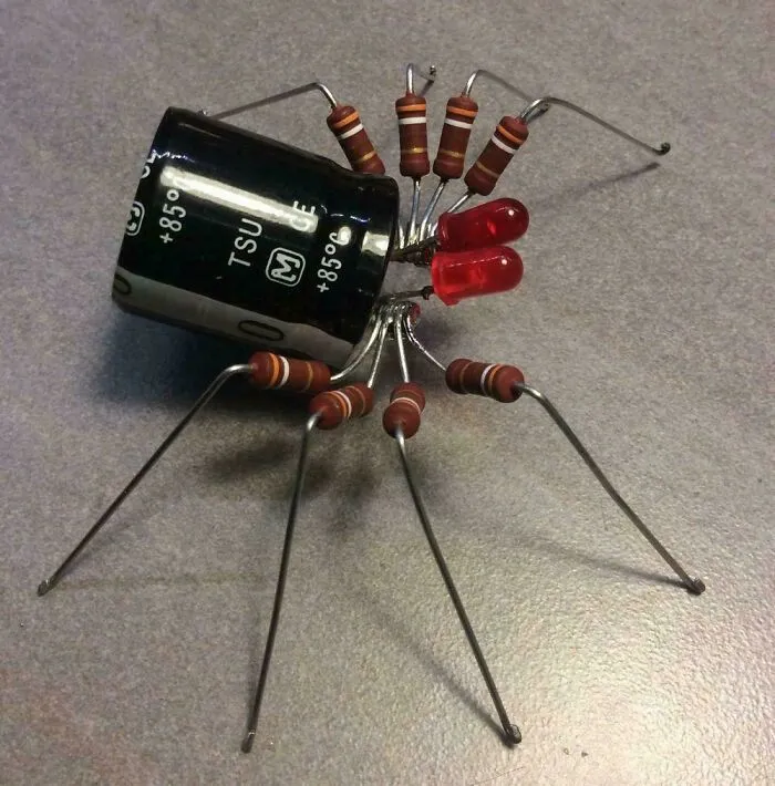 Elektronický pavúk z rezistorov, LED diód a kondenzátora na šedom povrchu, kreatívny techno dizajn.