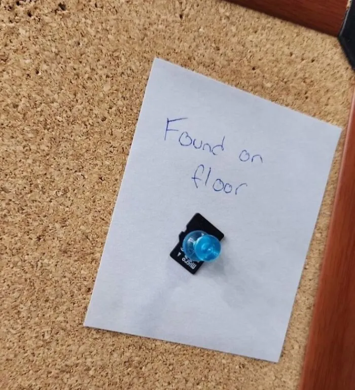 Papier s textom found on floor pripnutý špendlíkom na nástenke. Pod ním microSD karta.
