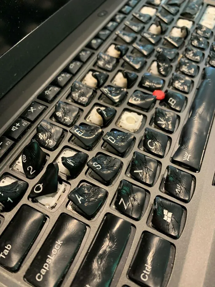 Polámaná klávesnica notebooku s poškodenými a popadanými klávesmi.