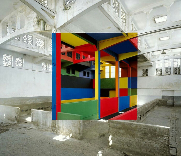 Farebné geometrické tvary v bielej industriálnej hale, spájajúce moderné umenie s architektúrou minulosti.