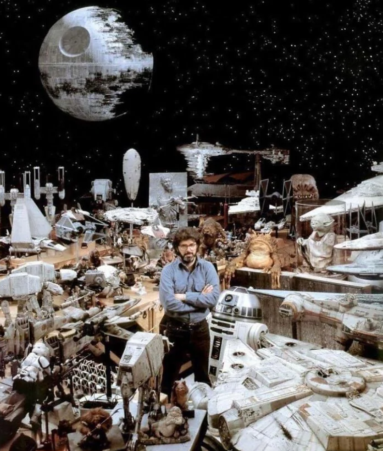 Muž stojí medzi modelmi lodí a postáv zo Star Wars, na pozadí Hviezda smrti a vesmír.