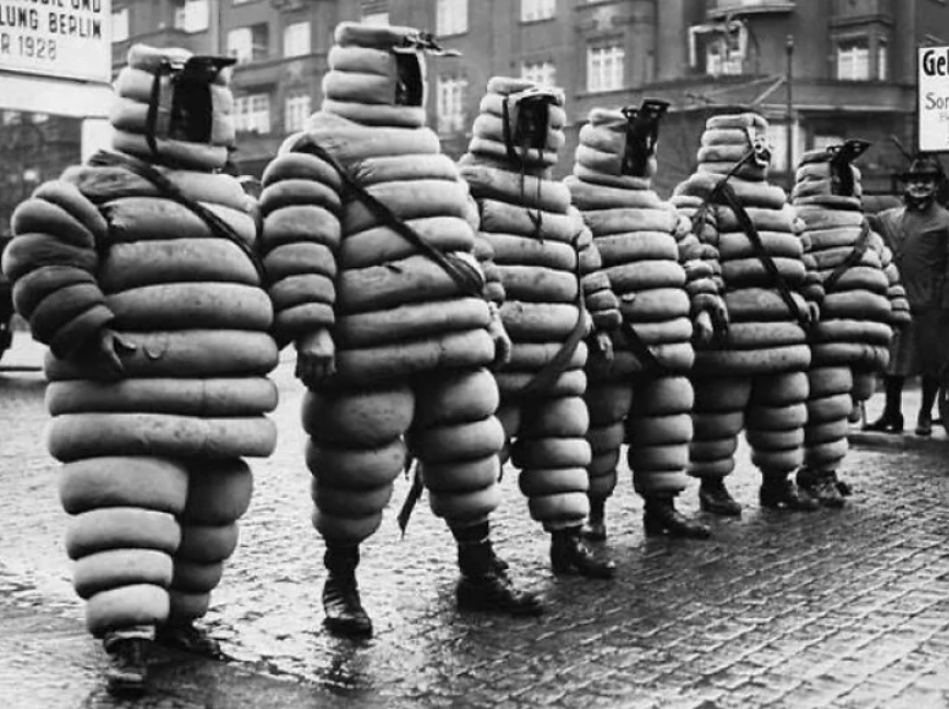Skupina ľudí v retro kostýmoch z pneumatik na ulici, historická fotografia.