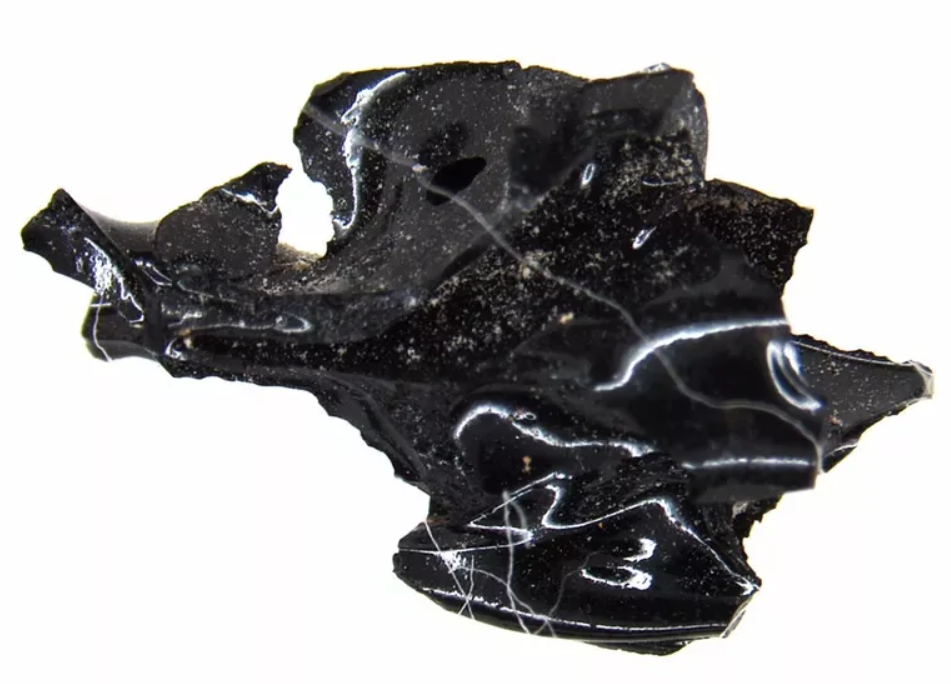 Čierny obsidián, kameň so zrkadlovým leskom a nepravidelným tvarom na bielom pozadí.
