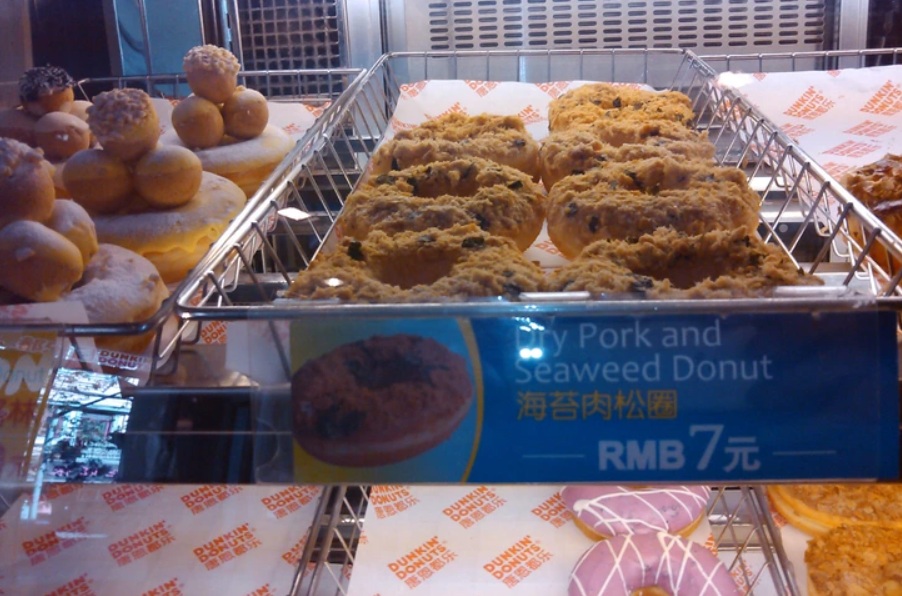 Donuty s bravčovým a morskými riasami na poličke pekárne v Dunkin' Donuts, cena 7 RMB.