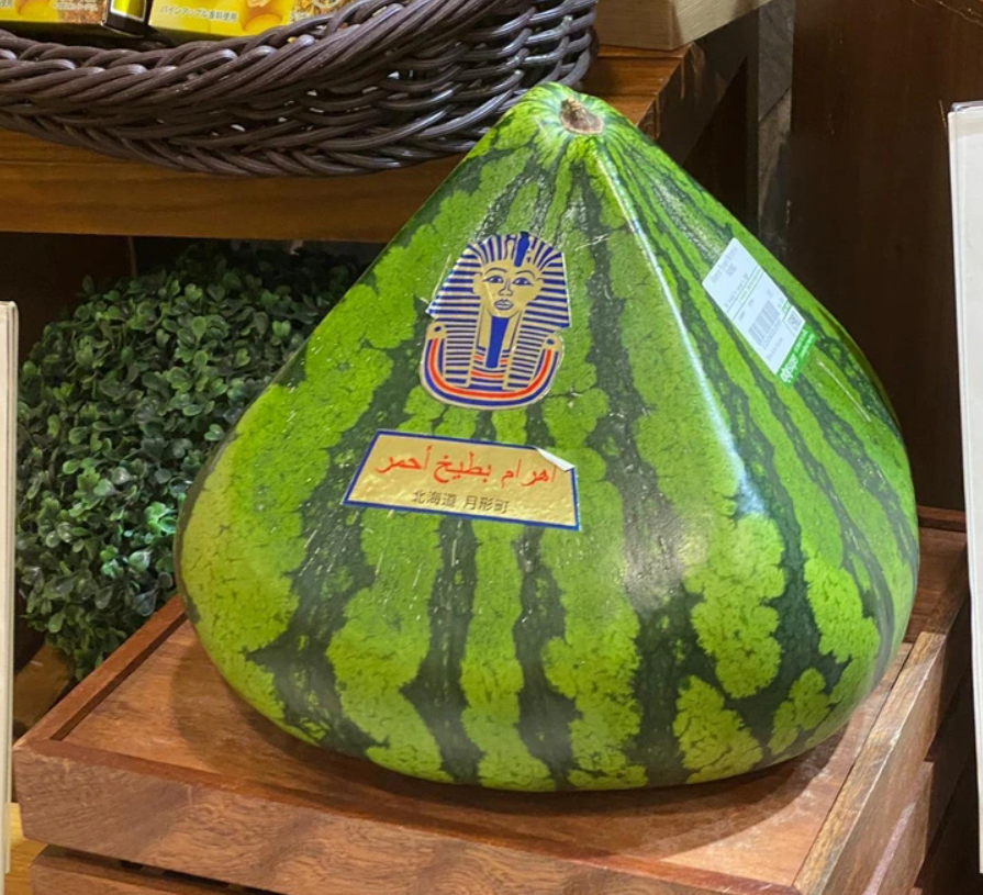 Melón s pyramídovým tvarom a etiketou v predajnom priestore.