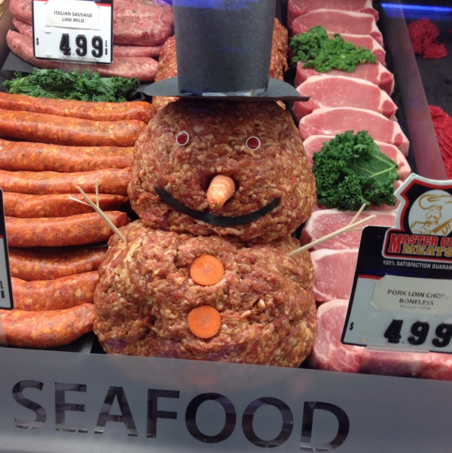 Snehuliak z guľatých potravinových častí pri pulte s nápisom SEAFOOD.