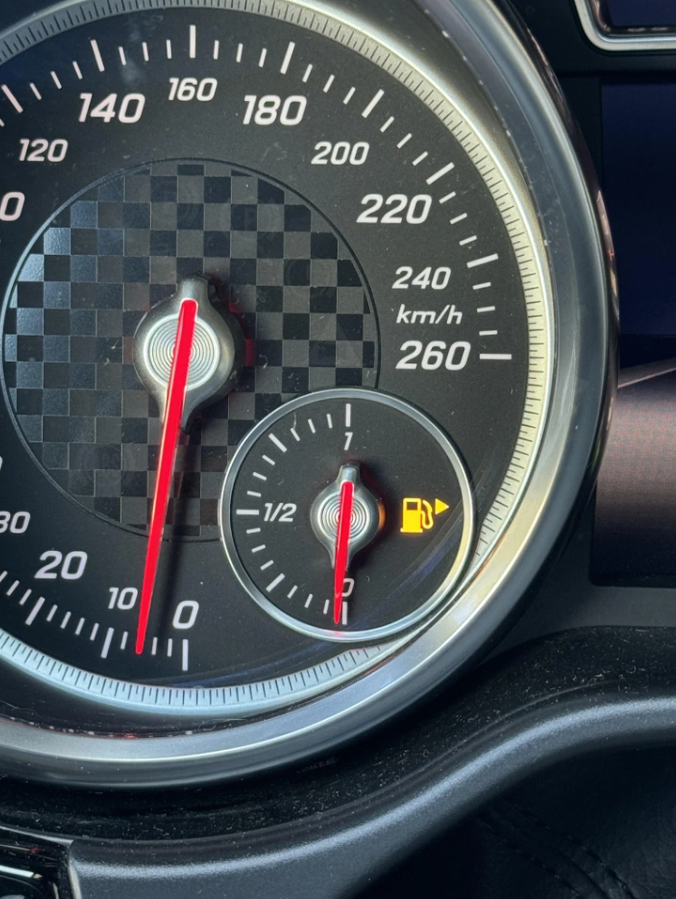 Rýchlomer auta ukazuje 0 km/h, nízky stav paliva signalizovaný ikonou.