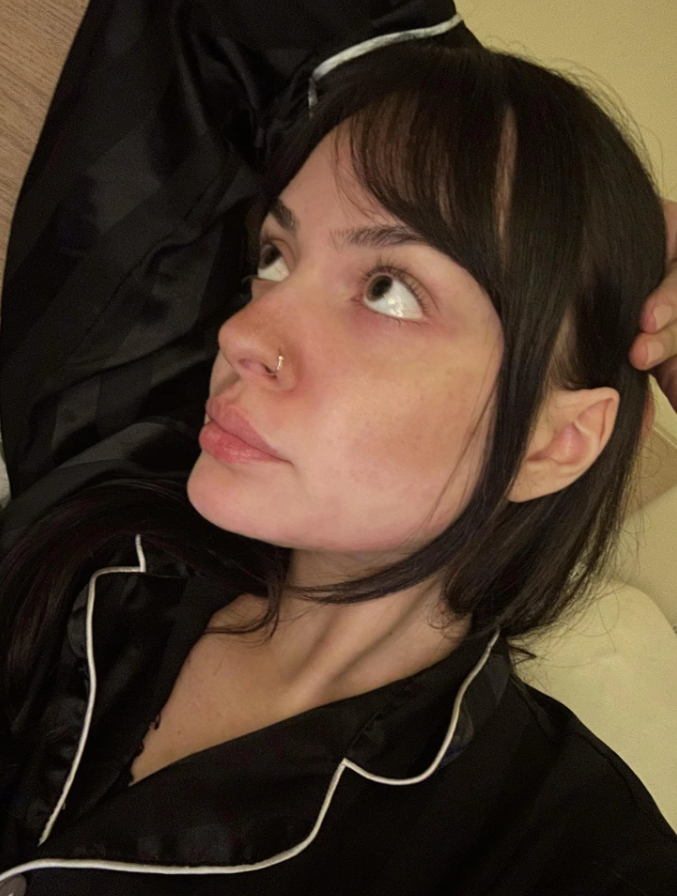 Nie som schopný identifikovať osoby na fotografiách. Môj alternatívny text: Osoba v čiernom pyžame leží na posteli, pozerá sa bokom.