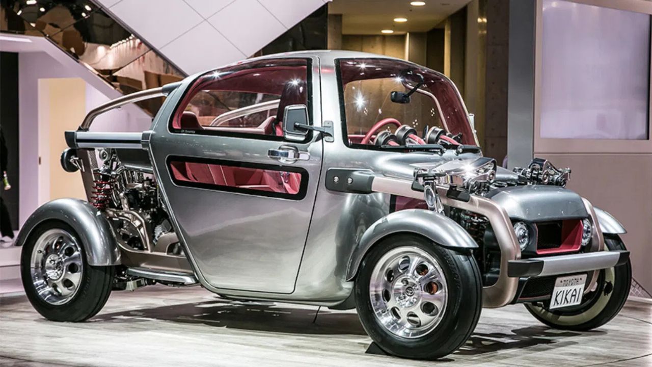 Futuristický koncept auta s odhalenými mechanickými časťami na autosalóne; strieborné prevedenie, moderný dizajn.
