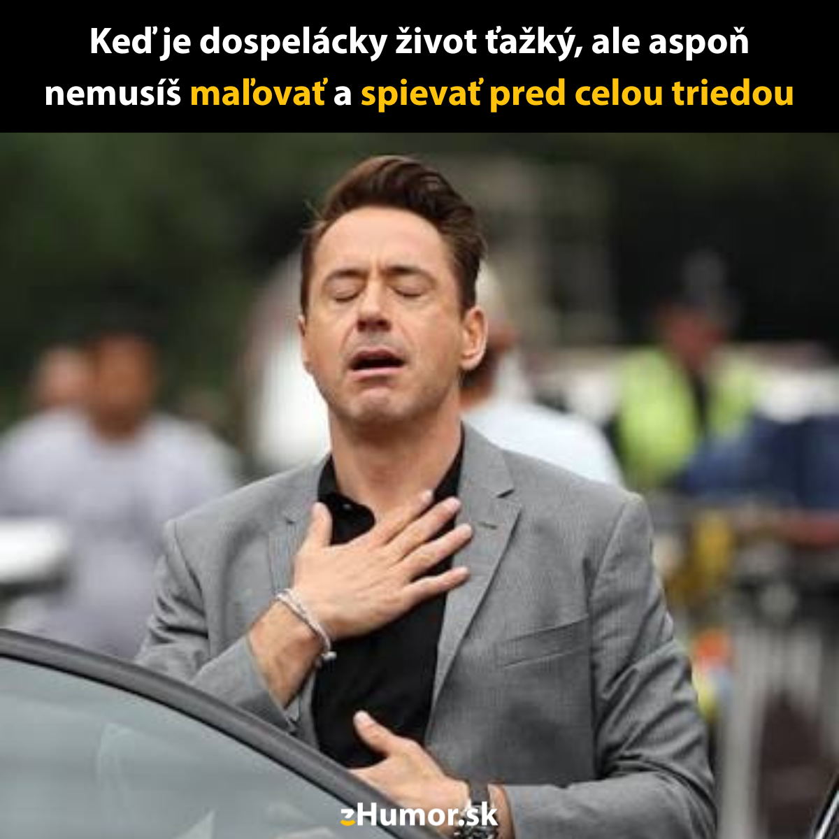 Osoba v saku so zatvorenými očami a rukou na hrudi vonku, s úľavou na tvári.