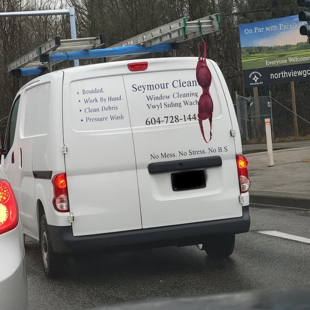 Dodávka s nápisom Seymour Cleaning a nezvyčajným doplnkom na zadných dverách na frekventovanej ceste.