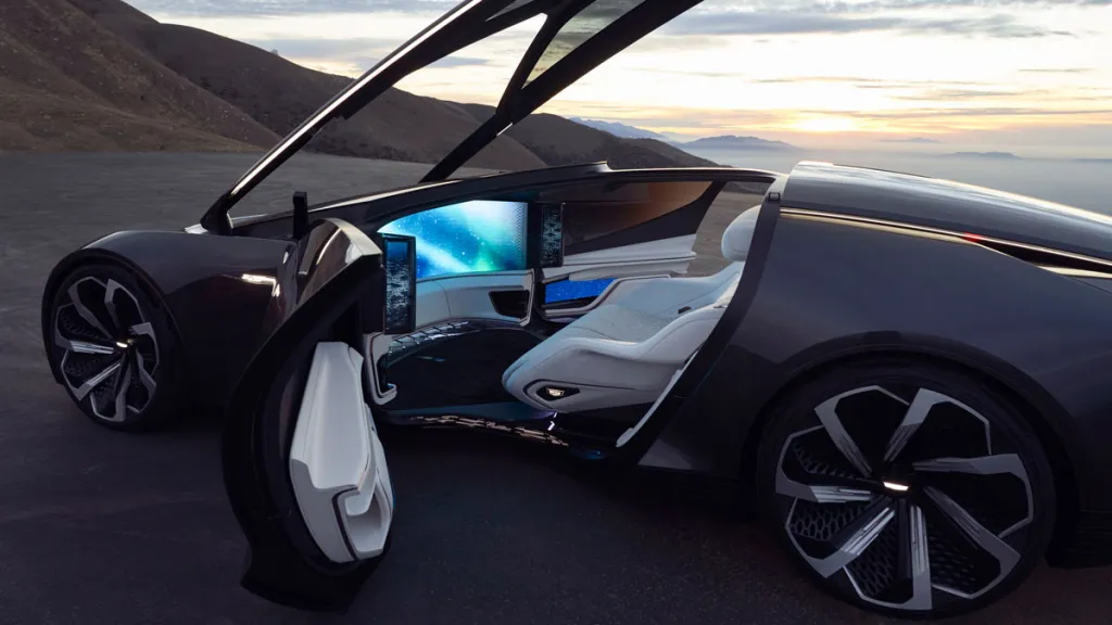 Futuristické auto s otvorenými dverami, luxusný interiér so sedačkami, palubná doska a obrazovky pri západe slnka v pozadí.